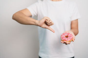 woman hand hold pink Donut, choose stop eating sweet is Unhealthy ealthy food. Dieting control,...