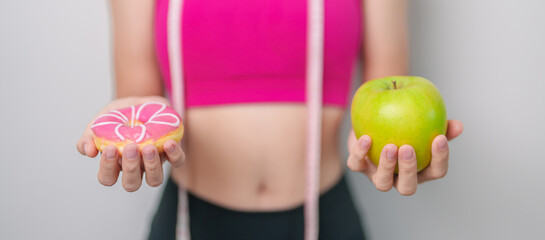 woman hand hold green Apple and donut, female fitness choose between fruit is Healthy and sweet is...