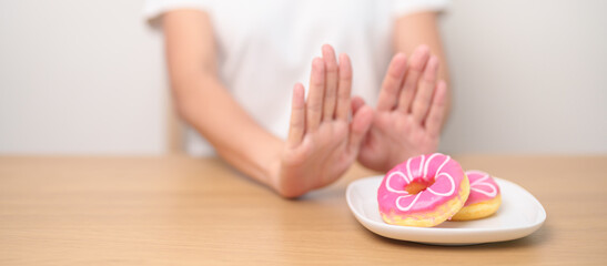 woman hand reject donut dessert, female refuse Unhealthy junk food. Dieting control, Weight loss,...