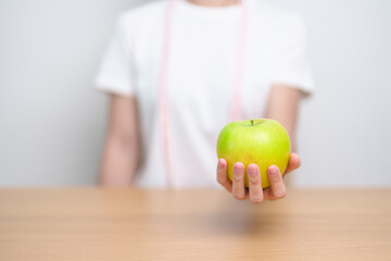 woman hand hold green Apple with tape measure, happy female choose fruit is Healthy food. Dieting...