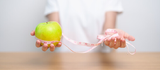 woman hand hold green Apple with tape measure, happy female choose fruit is Healthy food. Dieting...