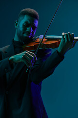 Elegant music performance of a man in a suit playing violin in front of a vibrant blue background