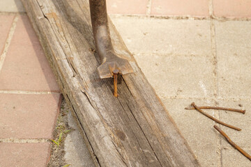 Pulling a nail out of a board using a nail puller.