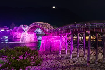 Kintai Bridge Illuminated at night. Cherry blossoms along the Nishiki River bank. The Sakura festival. Iwakuni, Yamaguchi Prefecture, Japan.