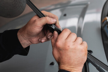 a mechanic changing and fixing a windshield wiper with his hands