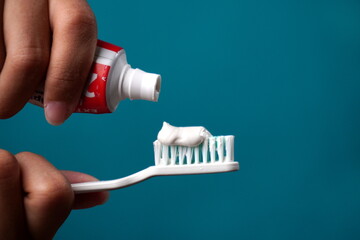 close up holding toothbrush with toothpaste isolated blue background