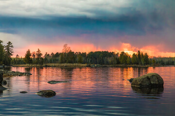 A storm front approaches over Boulder Lake near Duluth Minnesota as the sun sets in the distance on a beautiful spring evening