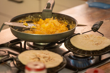 Colombian Breakfast Delight: Arepas and Scrambled Eggs. Freshly baked arepas sizzle on the stove while a pan of fluffy scrambled eggs awaits. The aroma of traditional Colombian flavors fills the air
