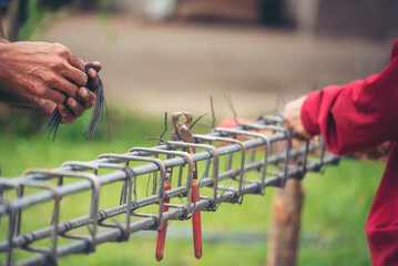 Construction Men hands bending cutting steel wire fences bar reinforcement of concrete work. Worker...