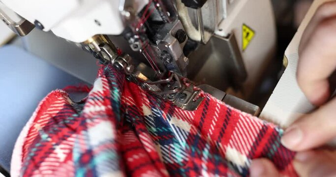 Worker sews vibrant clothing pieces using overlock machine