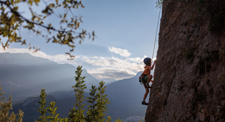 rock climber boy. child is practicing rock climbing. summer camp. sport in nature. cute teenager climbing on a rock with belay
