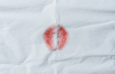 Red lipstick kiss on white tissue paper background.