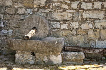Ancient stone grain mill against stone wall