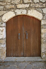 Old wooden door with arch on stone house