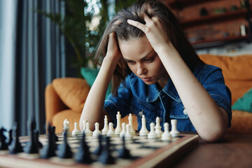A woman feeling stressed while playing chess on a couch at home, contemplating her next move