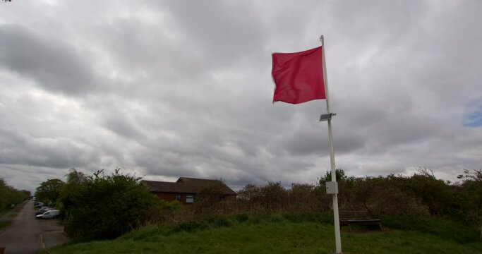 red danger flag flying in blustery wind right of frame