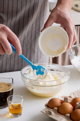 man wearing apron cooking tiramisu at kitchen