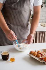 man wearing apron cooking tiramisu at kitchen
