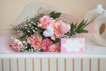 Pink rose bouquet with hearts and babys breath on table with card