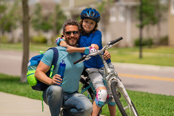Obraz premium Happy loving family. Father and son hugging. Happy playful dad with excited kid son riding a bicycle on weekend. Sporty family. Fathers day. Father teaching and support child.