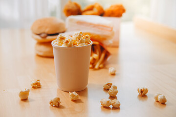 A bucket of popcorn, top-view, warm colors, light brown wooden background, flat lay, daylight macro close-up