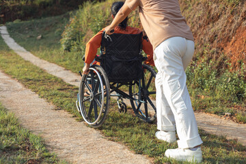 Senior women with wheelchair and care helper walking park