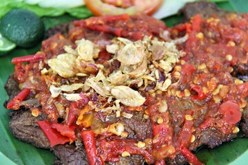 Empal Penyet consists of deep-seated beef cooked with kitchen spices such as bay leaves, galangal, lime leaves, tamarind, shallots, garlic, and many more.