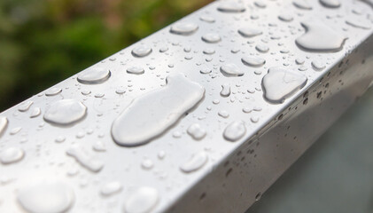 Drops of water from rain on a metal railing