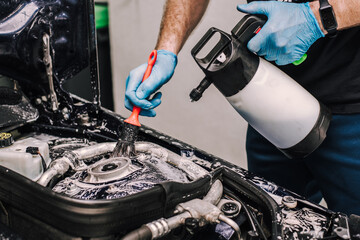 Person wearing gloves cleaning the car engine and interior parts