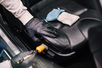 Man cleaning inside of black car with rubber brush