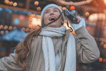 laughing woman taking pictures with vintage camera  on Christmas market 