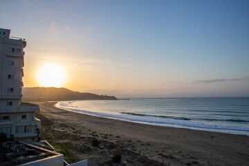 青とオレンジのグラデーションの空になった小さな湾状の海岸の朝焼け横フレーム