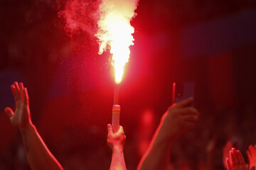 Details with the hands of a man holding a torch inside during a football (soccer) game