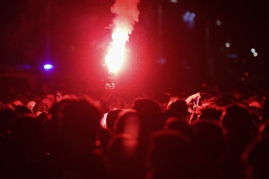 Details with the hands of a man holding a torch inside during a football (soccer) game