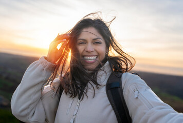 enjoying indian woman reaching destination taking selfie on mountain landscape at sunset