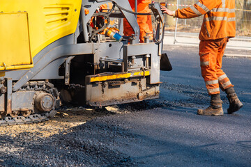 Asphalt paver hot tarmac with operator laying new road construction site	