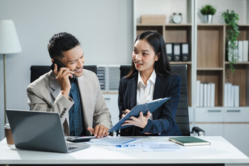 Business documents on office table with tablet and laptop computer and chart and two colleagues...