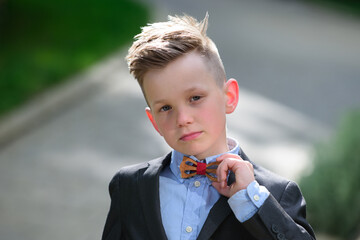 Fashion kid boy in suit and bow tie. Lifestyle portrait of cute kid outdoors. Summer kids outdoor...