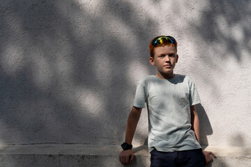 Child near the wall of a house on a summer sunny day with reflexes and shadows