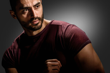 Brutal style portrait of handsome muscular young man posing on dark background, Brooding intensity:...