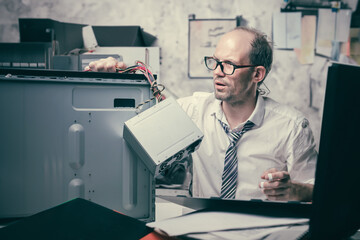 a non-professional man is trying to repair a computer, he is upset, depressed, tense