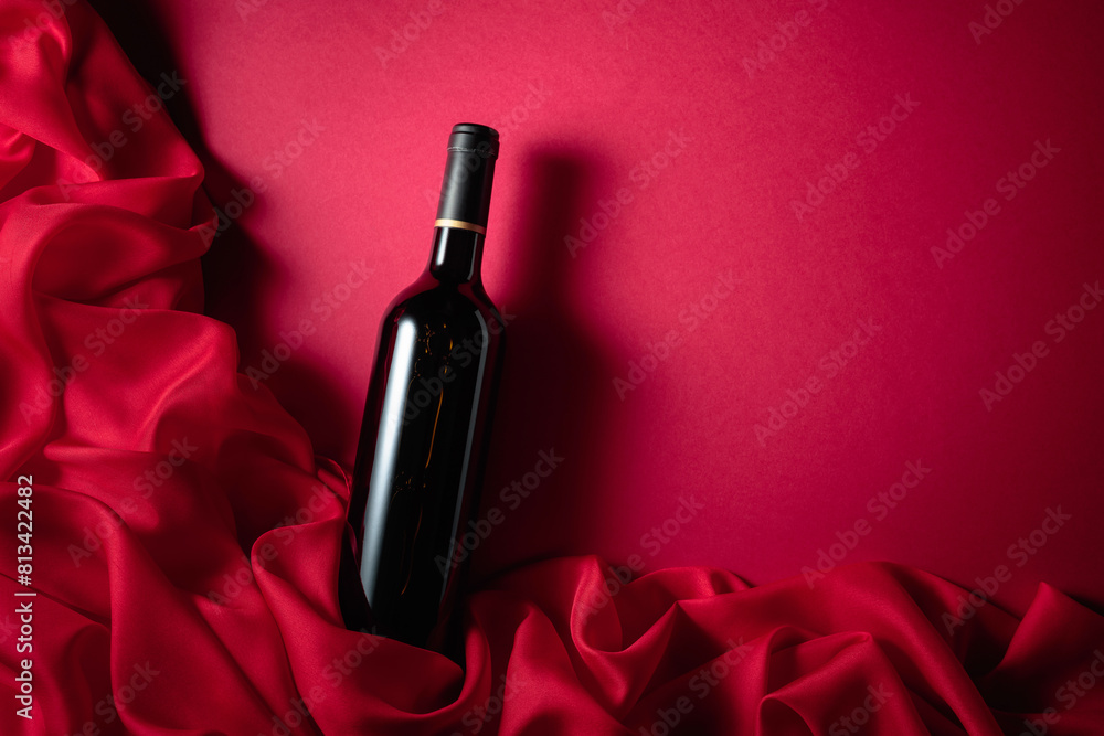 Wall mural Bottle of red wine on a red background.