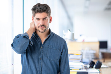 A portrait of unhappy mature man standing at the office and feeling pain in neck