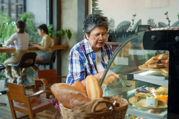 Asian Woman Diligence of seasoned barista evident as she engages with technology, bakery's goods on...