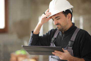 Disappointed construction worker checking tablet