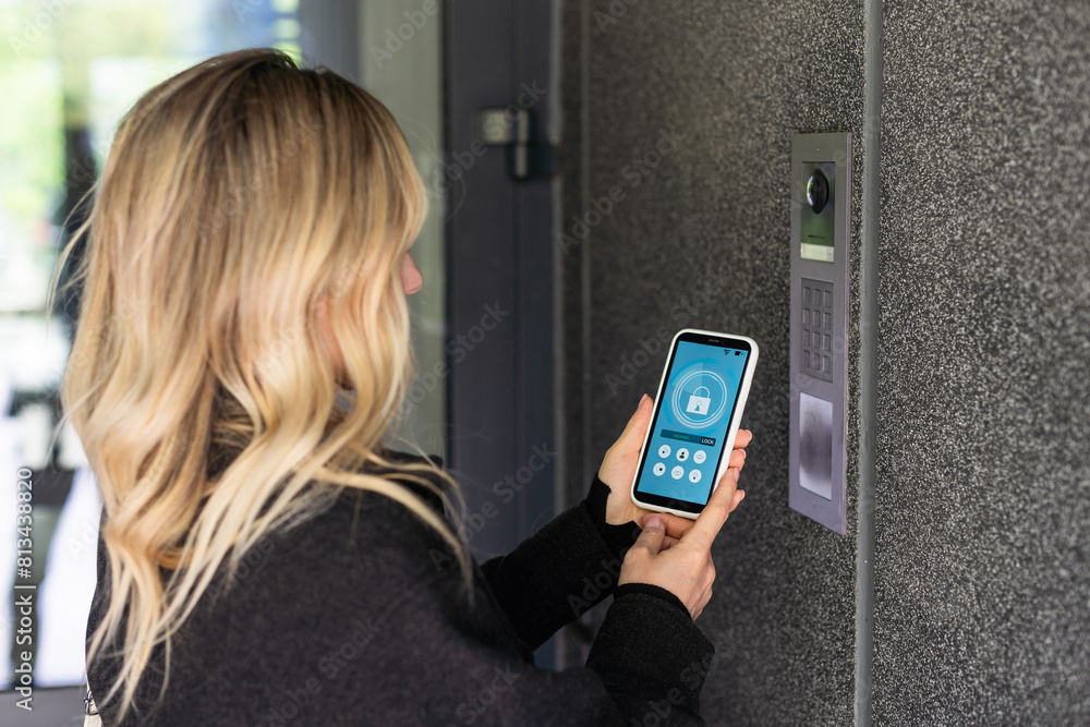 Poster smiling woman setting home security system with help of mobile application.