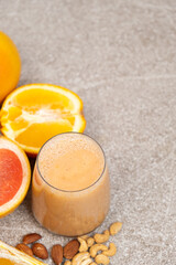 Fruit nut smoothie in a glass on a stone background, copy space for text