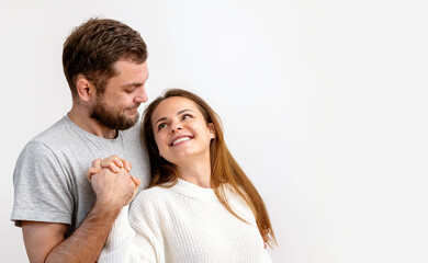 Happy loving young adult couple hugging on white background. Heterosexual couple in love.