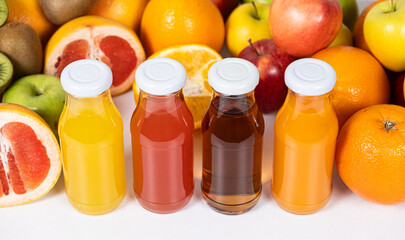 Different types of fruit juices - orange, grapefruit, apple and multifruit in glass bottles.
