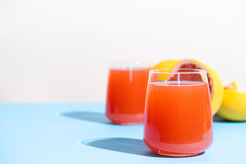 Grapefruit juice in a glass on blue background, copy space for text